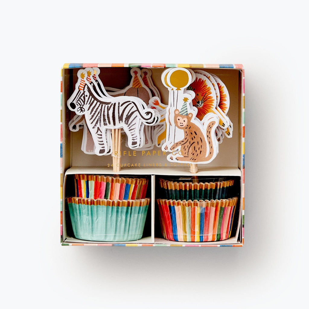 cupcake kit in box shows striped cupcake liners with gold trim and mint cupcake liners with gold trim. Topers are on toothpick - zebra wearing a party  hat, a monkey wearing a party hat holding a balloon, there is a lion in behind the monkey and the top of an elephants head behind the zebra.